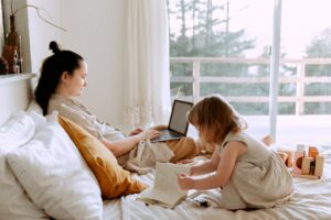 Woman in bed on laptop with child